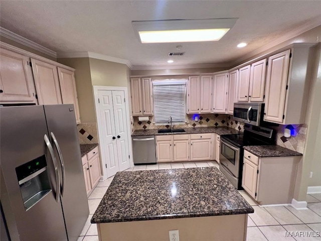 kitchen featuring sink, light tile patterned floors, appliances with stainless steel finishes, a center island, and tasteful backsplash