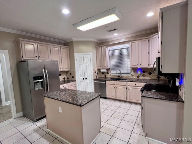 kitchen with sink, light tile patterned floors, ornamental molding, appliances with stainless steel finishes, and a kitchen island