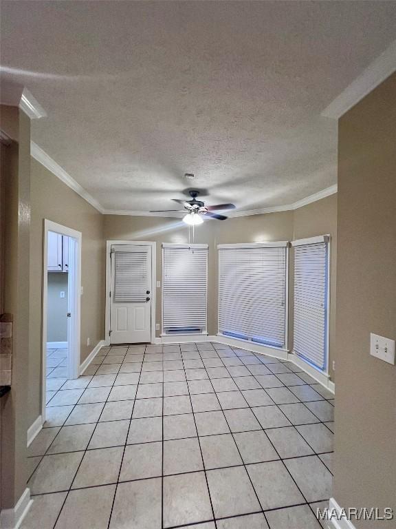 empty room with light tile patterned floors, ornamental molding, a textured ceiling, and ceiling fan