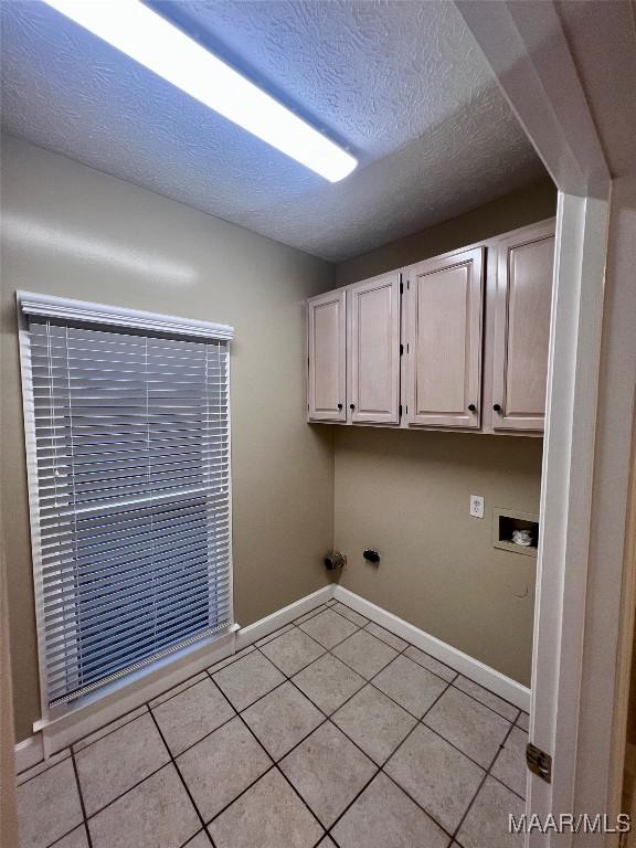 laundry area with cabinets, hookup for a washing machine, light tile patterned floors, and a textured ceiling