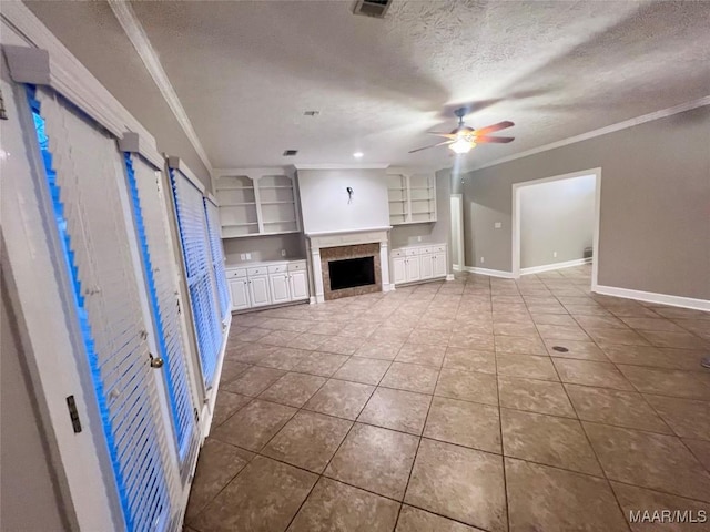 unfurnished living room featuring ceiling fan, built in shelves, ornamental molding, and a textured ceiling