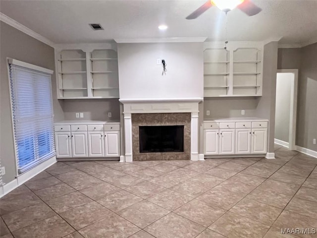 unfurnished living room with crown molding, light tile patterned floors, a fireplace, and ceiling fan