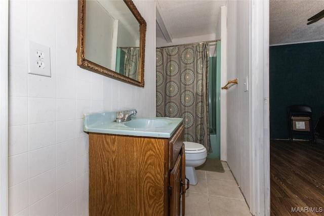 full bathroom with tile patterned flooring, vanity, shower / bath combination with curtain, a textured ceiling, and toilet