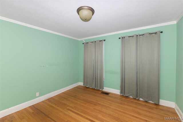 spare room featuring hardwood / wood-style floors and crown molding