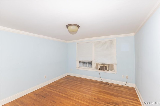 empty room featuring cooling unit, crown molding, baseboards, and wood finished floors