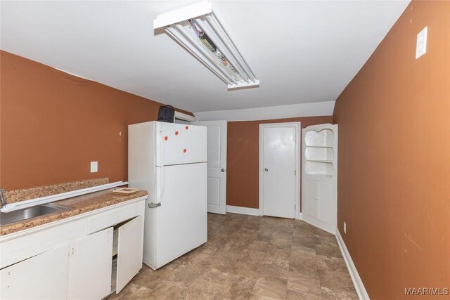 kitchen featuring white refrigerator, white cabinetry, and sink