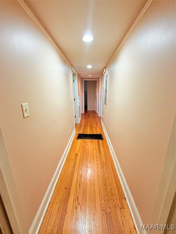 hall with light wood finished floors, baseboards, crown molding, and recessed lighting