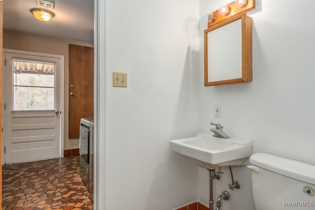 bathroom with toilet, washer / dryer, and sink