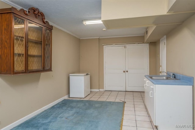 laundry area featuring light tile patterned flooring, ornamental molding, sink, and a textured ceiling