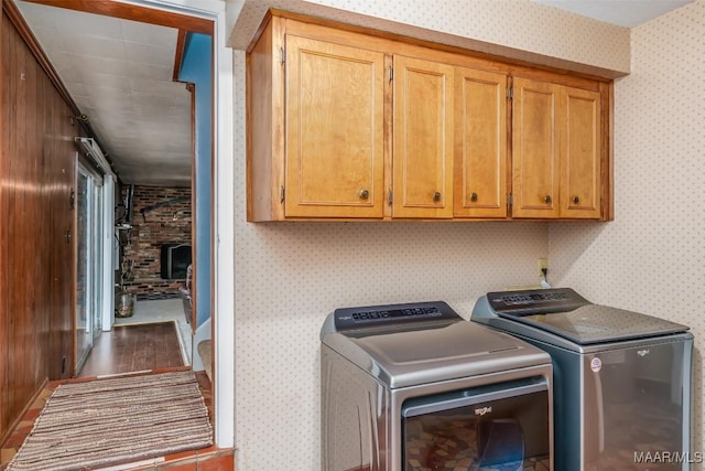 laundry area featuring cabinets, a brick fireplace, and washer and dryer