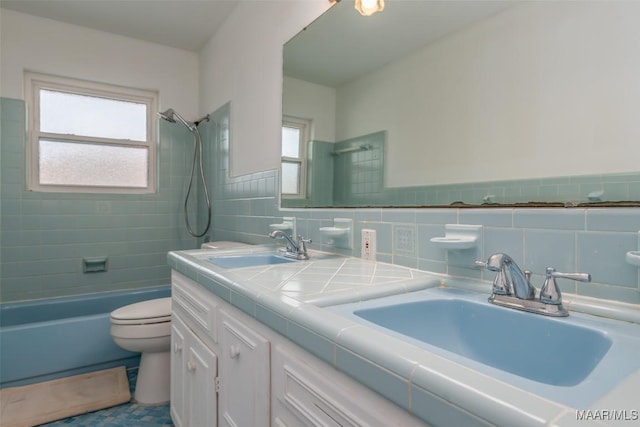 full bathroom featuring tile walls, vanity, tiled shower / bath, and toilet