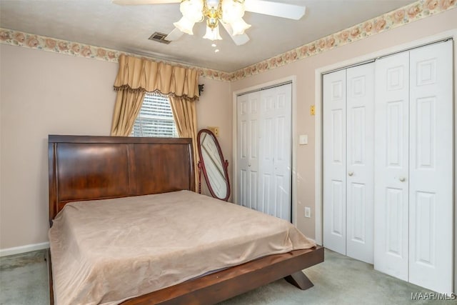 bedroom featuring ceiling fan, light carpet, and two closets