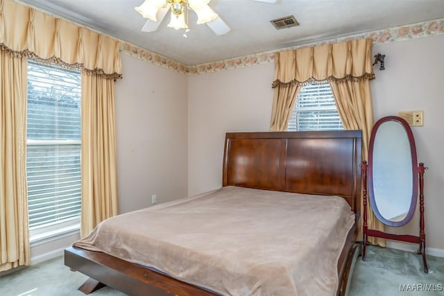 bedroom featuring multiple windows, light colored carpet, and ceiling fan