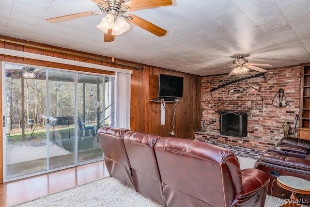 living room with ceiling fan, brick wall, light wood-type flooring, and wood walls