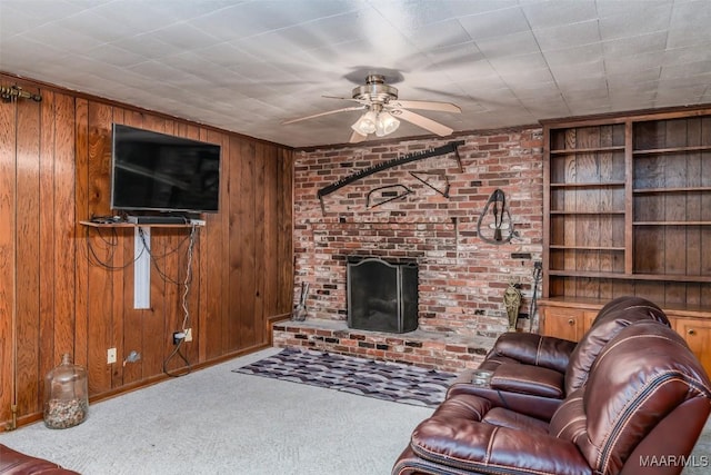 living room with a brick fireplace, wooden walls, ceiling fan, and carpet flooring