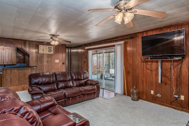 carpeted living room with ceiling fan and wooden walls