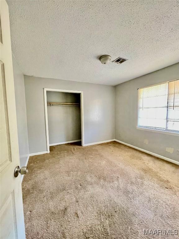 unfurnished bedroom with a closet, a textured ceiling, and carpet flooring