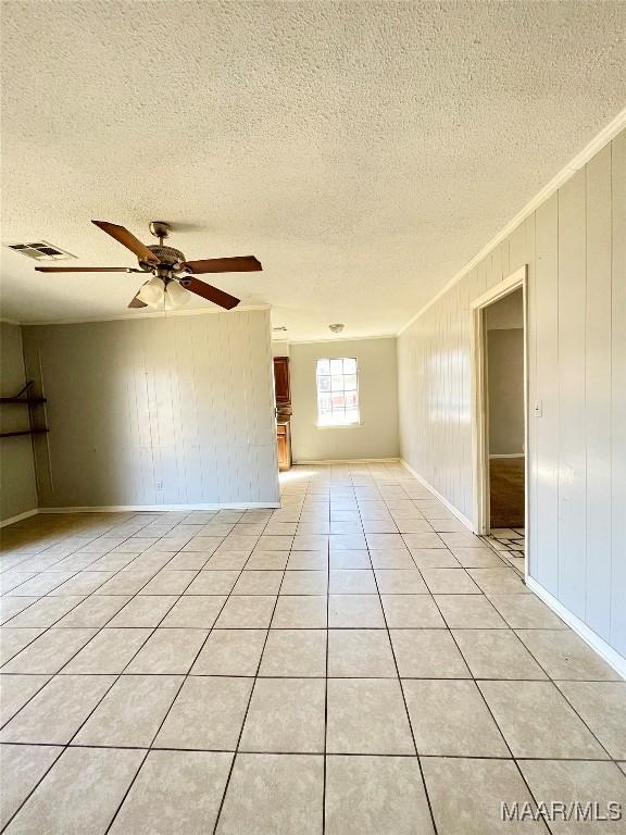 empty room featuring ornamental molding, light tile patterned floors, a textured ceiling, and ceiling fan