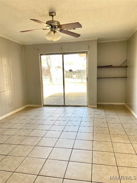 tiled empty room featuring crown molding, a textured ceiling, and ceiling fan