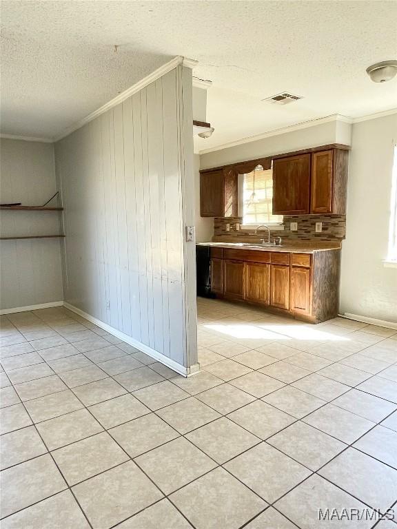 kitchen with crown molding, sink, a textured ceiling, and wood walls