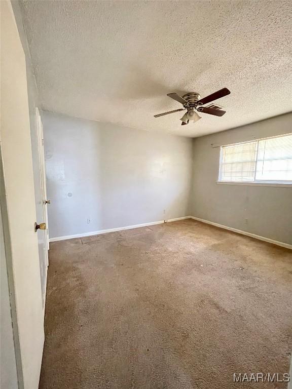 empty room featuring a textured ceiling, carpet floors, and ceiling fan