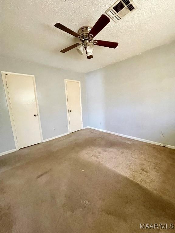 carpeted empty room with ceiling fan and a textured ceiling