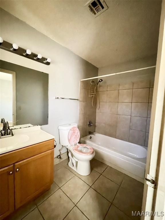 full bathroom with tile patterned flooring, tiled shower / bath, vanity, and toilet