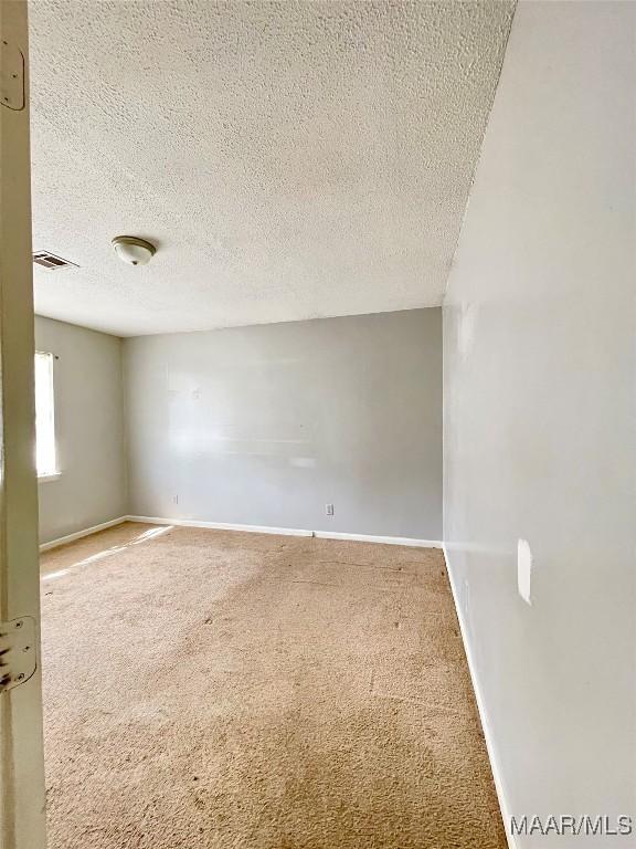 carpeted empty room with a textured ceiling