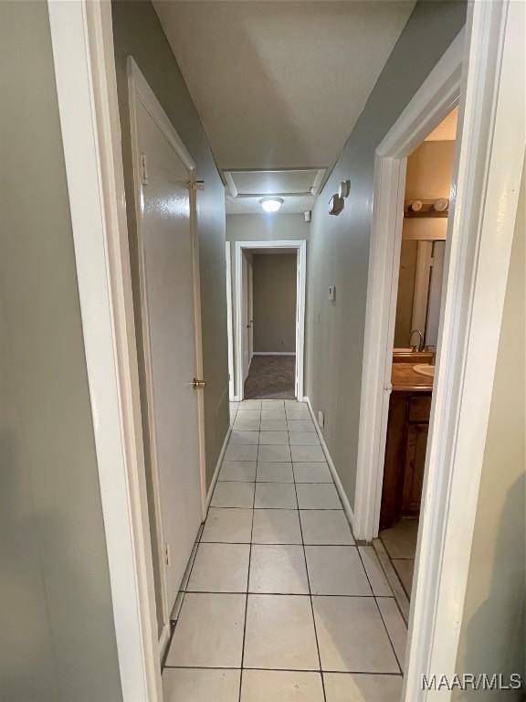 corridor with light tile patterned floors and baseboards