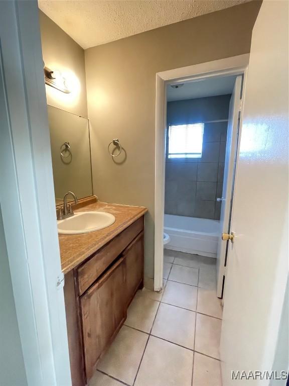 bathroom featuring a textured ceiling, toilet, vanity,  shower combination, and tile patterned floors