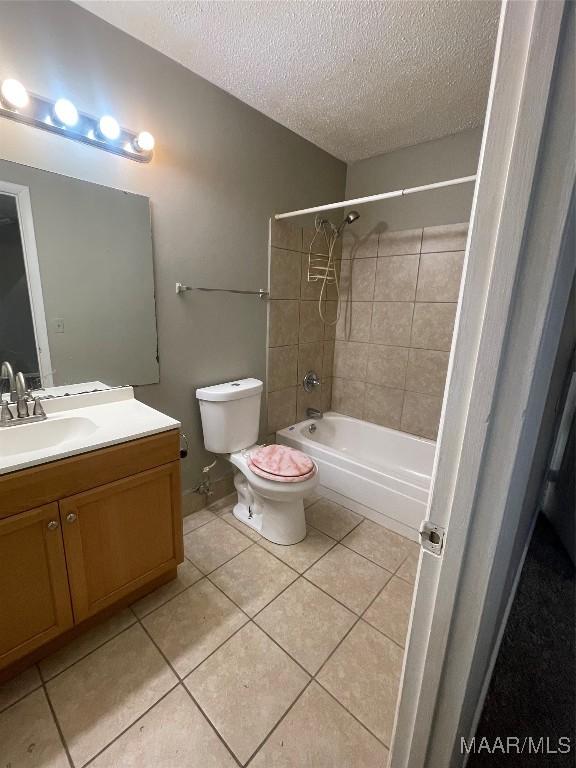 bathroom featuring a textured ceiling, vanity, toilet, and tile patterned floors