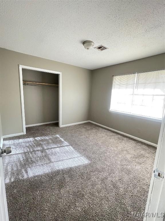 unfurnished bedroom featuring carpet, visible vents, and baseboards