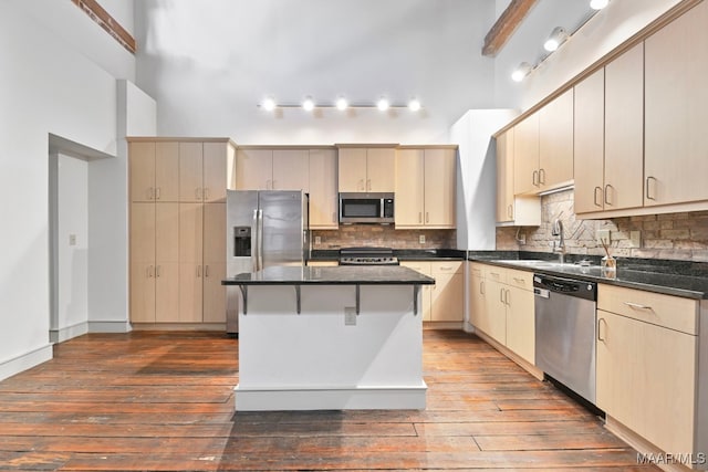 kitchen featuring sink, tasteful backsplash, wood-type flooring, a kitchen island, and stainless steel appliances