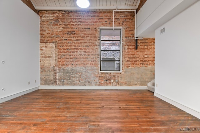 empty room with brick wall and hardwood / wood-style floors