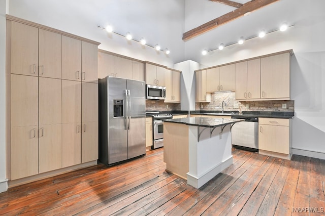 kitchen with a center island, dark hardwood / wood-style flooring, a towering ceiling, stainless steel appliances, and backsplash