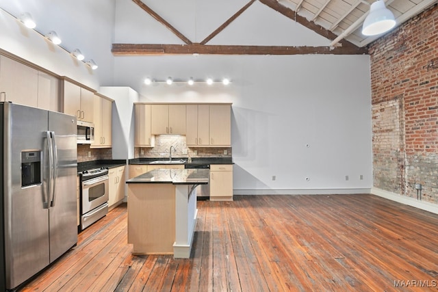 kitchen featuring sink, stainless steel appliances, a center island, high vaulted ceiling, and cream cabinets