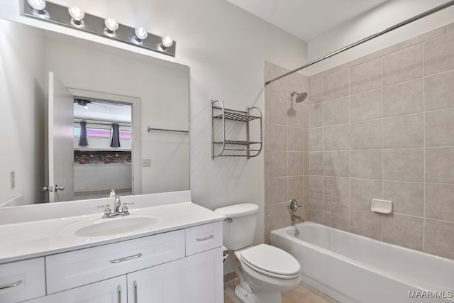 full bathroom featuring tiled shower / bath, vanity, and toilet