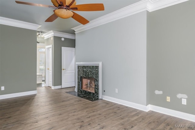 unfurnished living room featuring ceiling fan, a high end fireplace, ornamental molding, and wood-type flooring