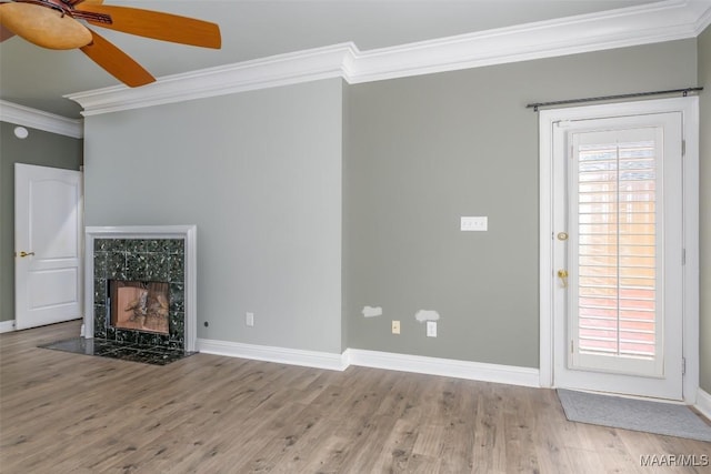 unfurnished living room featuring ornamental molding, a tiled fireplace, hardwood / wood-style floors, and a wealth of natural light