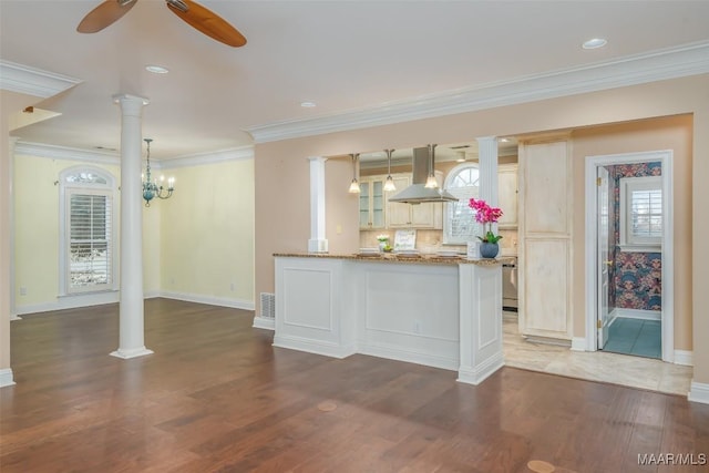 interior space with crown molding, ceiling fan, dark hardwood / wood-style floors, island range hood, and ornate columns