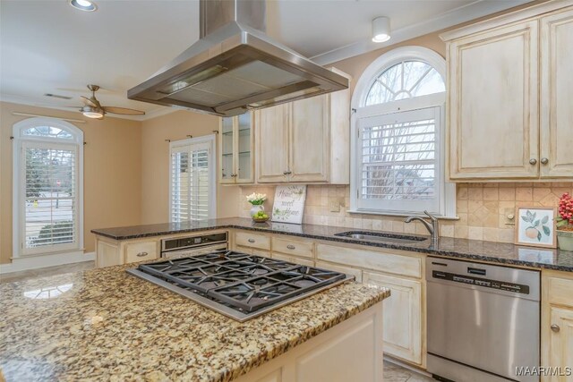 kitchen featuring island exhaust hood, stainless steel appliances, stone countertops, and sink