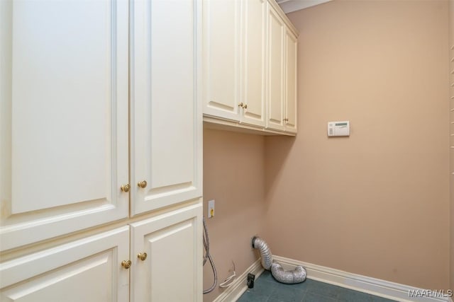 clothes washing area featuring dark tile patterned flooring and cabinets