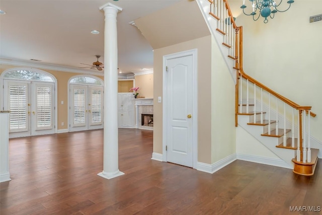 unfurnished living room with decorative columns, dark hardwood / wood-style flooring, ornamental molding, ceiling fan, and french doors