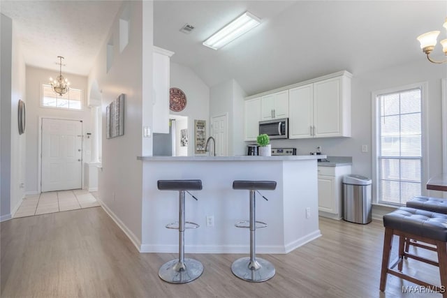 kitchen featuring white cabinetry, a notable chandelier, a kitchen breakfast bar, and kitchen peninsula