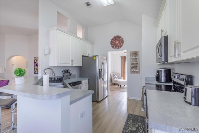 kitchen featuring a breakfast bar, sink, kitchen peninsula, stainless steel appliances, and white cabinets