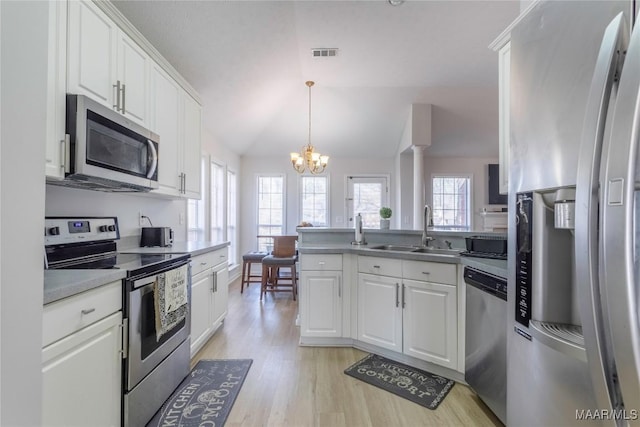 kitchen with lofted ceiling, sink, white cabinetry, decorative light fixtures, and appliances with stainless steel finishes