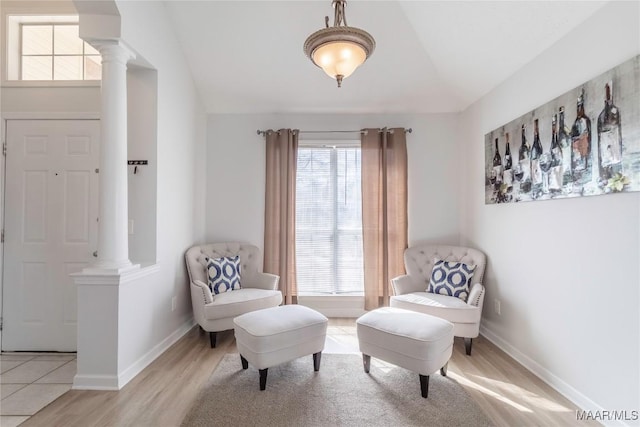 sitting room featuring vaulted ceiling, light hardwood / wood-style floors, and decorative columns