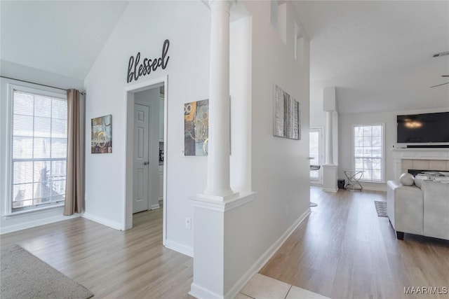 hallway with decorative columns, lofted ceiling, and light hardwood / wood-style floors