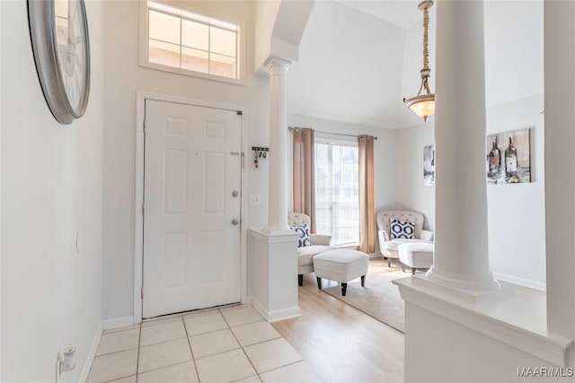 foyer entrance with decorative columns and light tile patterned floors