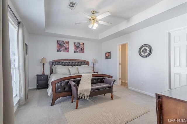 bedroom with light carpet, ceiling fan, and a tray ceiling